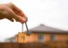 Sticker Shock: Manhattan Rents Go Nuclear Hand holding house key with wooden house keychain