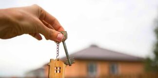 Hand holding house key with wooden house keychain