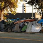 Street encampment with tarps and makeshift tents by roadside