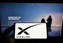 Smartphone showing Starlink logo in front of a computer screen