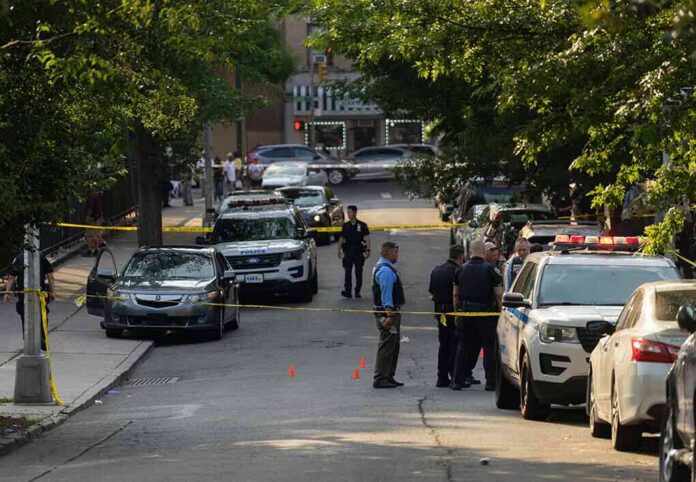 Police officers secure a residential street with patrol cars and yellow tape