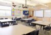 Empty classroom with tables, chairs, and a whiteboard