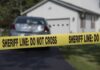 Sheriff line tape blocking a suburban driveway
