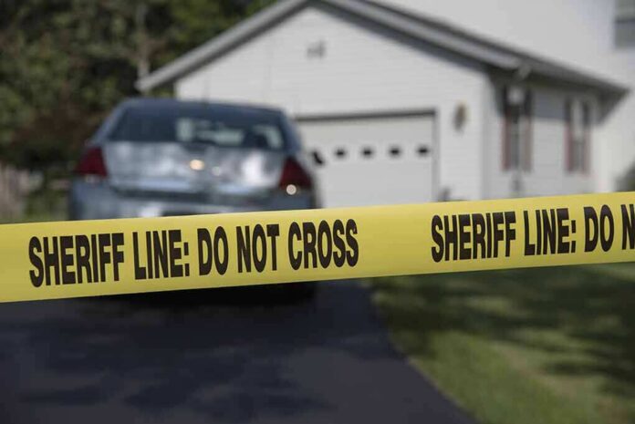 shutterstock_453232906 Sheriff line tape blocking a suburban driveway