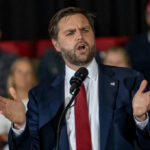Data Center Revolt Upends Michigan Man in suit speaking at a podium