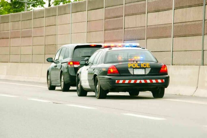shutterstock_1006978648 Police car with flashing lights stops a minivan on highway
