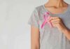 Breast Cancer Fight Becomes Political Brawl Person holding a pink ribbon on a gray shirt