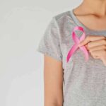 Breast Cancer Fight Becomes Political Brawl Person holding a pink ribbon on a gray shirt