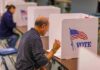 Man filling out ballot at voting booth