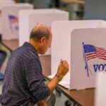 California Dumps ID At Polls Man filling out ballot at voting booth