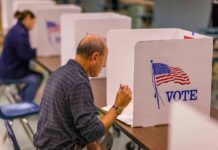 Man filling out ballot at voting booth