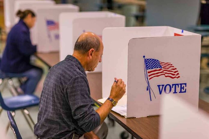 shutterstock_1046168680 Man filling out ballot at voting booth