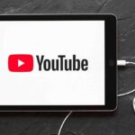 FTC vs YouTube: Rigged Rules Exposed? Tablet displaying YouTube logo with wired earphones
