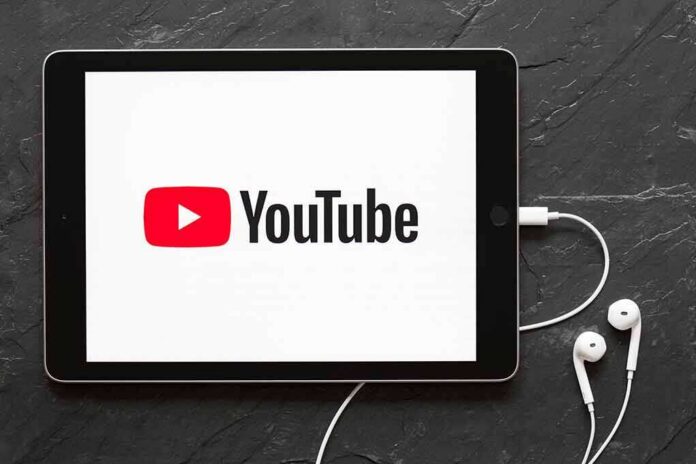shutterstock_1054927760 Tablet displaying YouTube logo with wired earphones