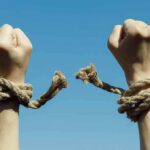 Oscar Rebel Cuffed During UN Chaos Hands breaking free from rope bindings against a clear blue sky