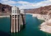 Record Low Threatens Southwest Power A large dam structure with two towers over a blue water reservoir surrounded by rocky mountains