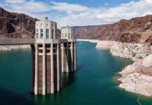 Record Low Threatens Southwest Power A large dam structure with two towers over a blue water reservoir surrounded by rocky mountains