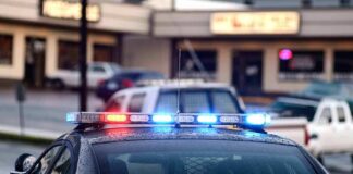 Police car with flashing red and blue lights in a parking lot