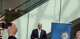 Man in a suit at a public event near a blue banner