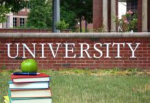 Stack of books with apple in front of university sign
