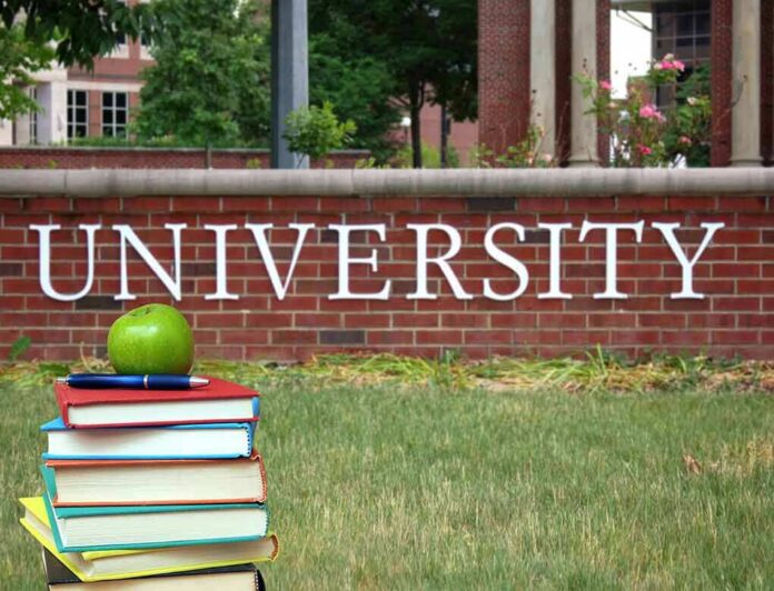 Stack of books with apple in front of university sign