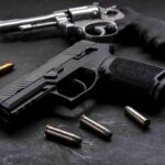 Grisly Find Triggers Massive Gun Bust Handgun and revolver with scattered bullets on dark surface
