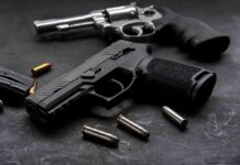 Grisly Find Triggers Massive Gun Bust Handgun and revolver with scattered bullets on dark surface
