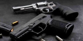 Handgun and revolver with scattered bullets on dark surface
