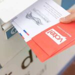 Last-Minute Mail Ballot Showdown Paused Hand dropping mail-in ballots into a drop box