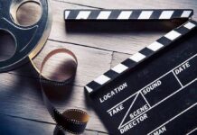 Film reel and clapperboard on wooden surface