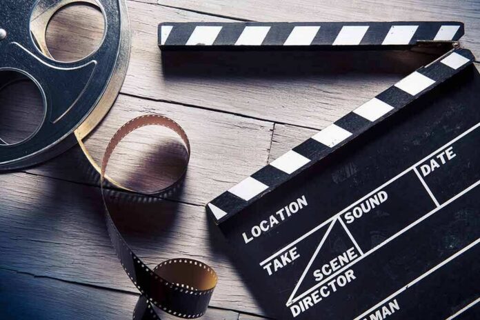 shutterstock_169841813 Film reel and clapperboard on wooden surface