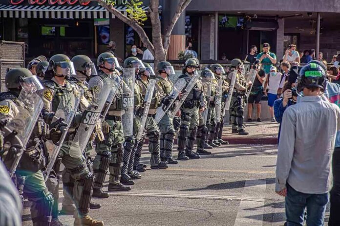 shutterstock_1756892879 Riot police in helmets and shields form a line on a city street