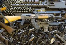 Assorted firearms and ammunition laid out in a dense pile