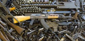 Assorted firearms and ammunition laid out in a dense pile