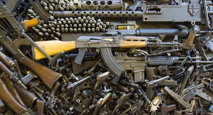 shutterstock_176722802 Assorted firearms and ammunition laid out in a dense pile