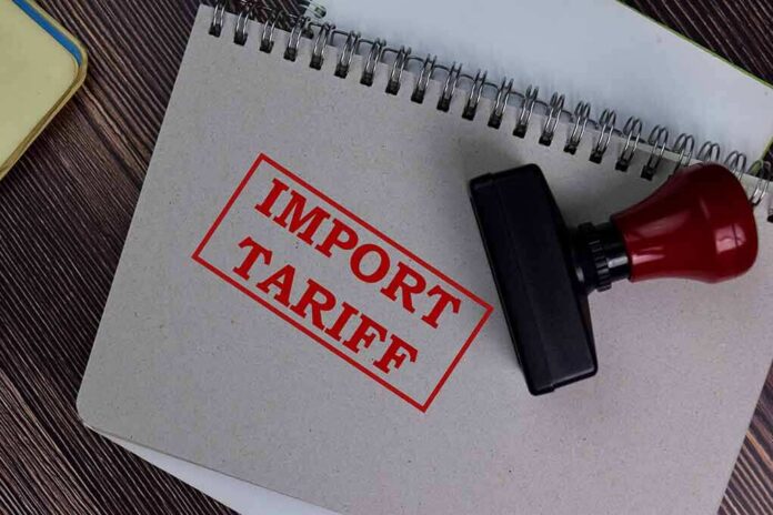 shutterstock_1773748721 Notebook with import tariff stamp and red-handled rubber stamp