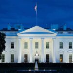 Congress Or Trump? Ballroom Fight Deepens White House illuminated at dusk with flagpole and columns