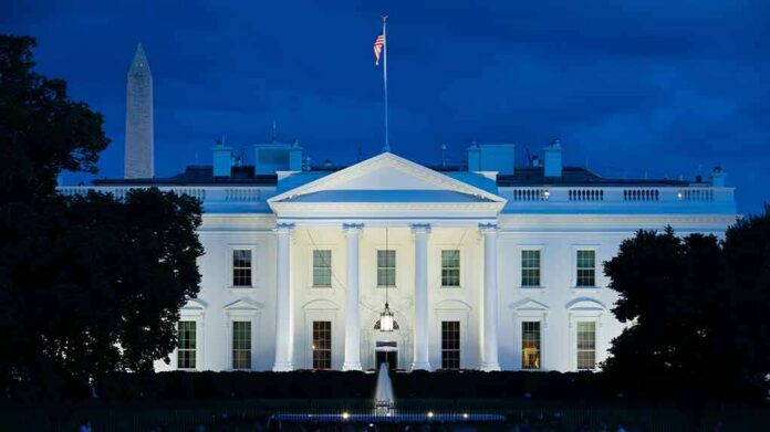 shutterstock_1817955236 White House illuminated at dusk with flagpole and columns