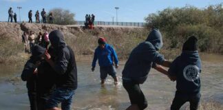 Group of people wading through a shallow river