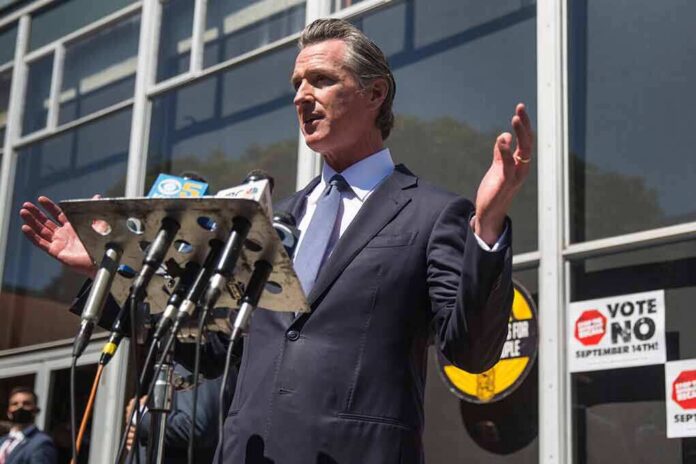 shutterstock_2041539359 Gavin Newsom speaks at a press conference with microphones outside a building