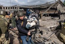 Ambulance Targeted After Suicide Bomb Rescuers carry a baby in a stroller through a destroyed bridge