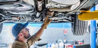 Mechanic inspecting underside of a car on a lift