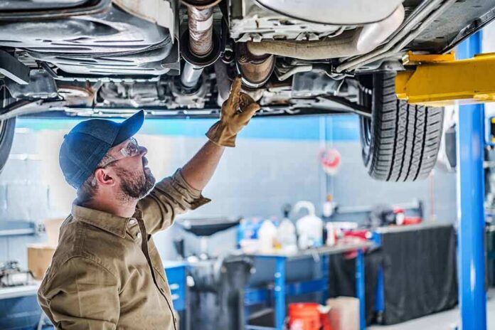 shutterstock_2246886761 Mechanic inspecting underside of a car on a lift