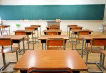 School Cash Twist Splits Democrats Empty classroom with rows of wooden desks facing a large chalkboard
