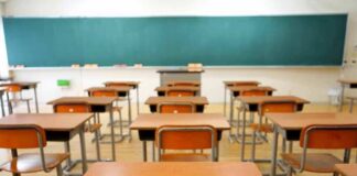 Empty classroom with rows of wooden desks facing a large chalkboard