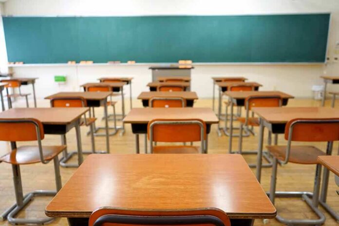 shutterstock_356921618 Empty classroom with rows of wooden desks facing a large chalkboard