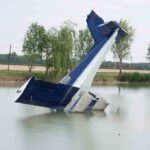 Near-Death Splash Stuns Congressman An abandoned aircraft partially submerged in a calm body of water surrounded by trees