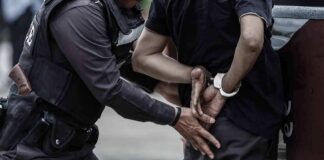 Police officer handcuffing a person against a vehicle