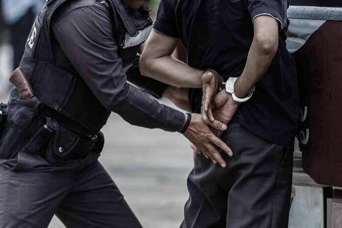 Police officer handcuffing a person against a vehicle