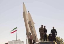 Iran Claims A Clash The U.S. Denies soldiers stand beside large missiles at outdoor display